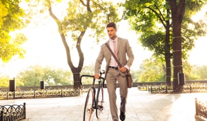 Man walking through a park with bicycle