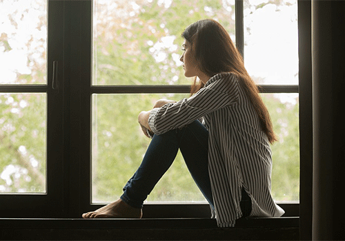 teen sitting by window